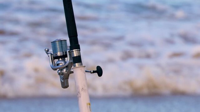 Close Up of Fishing Reel and Rod with Ocean Waves Background