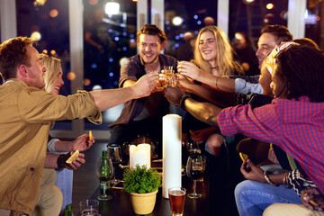 Cheers, shots and group of friends in night club for fun, bonding or celebration together. Smile, bokeh and people with alcohol drinks for toast at event, party or social gathering at happy hour. © Hinrichsen/peopleimages.com