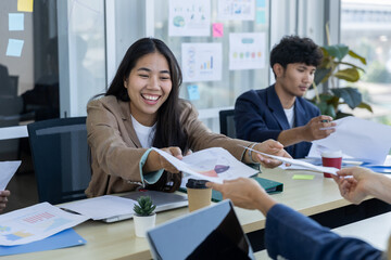Fototapeta premium Happy business team sharing financial reports during office meeting. Professionals exchanging documents and discussing charts. Corporate collaboration, teamwork and data analysis concept.