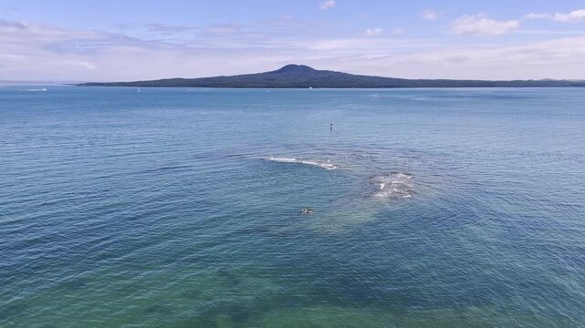 Scenic view of Rangitoto Island, a volcanic island in the Hauraki Gulf near Auckland, New Zealand. The island is a popular destination for hiking and exploring.