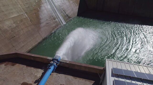 Hydropower station pumping water. Water outlet from dam wall. Howell Bunger valve in operation. Aerial view. Pressurized water outlet from dam wall. Water flowing from pumping in reservoir. Spain.