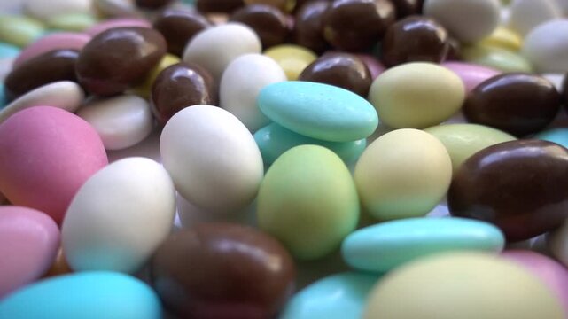 Pile of chocolate-covered almonds or colored pine nut almonds. Easter season.
