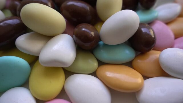 Pile of chocolate-covered almonds or colored pine nut almonds. Easter season.