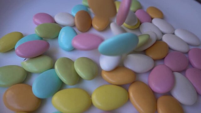 Pile of chocolate-covered almonds or colored pine nut almonds. Easter season.