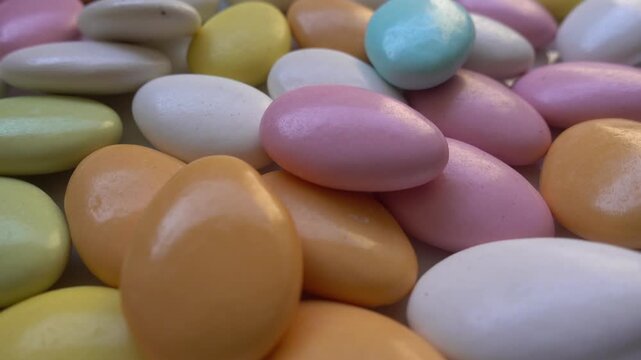 Pile of chocolate-covered almonds or colored pine nut almonds. Easter season.