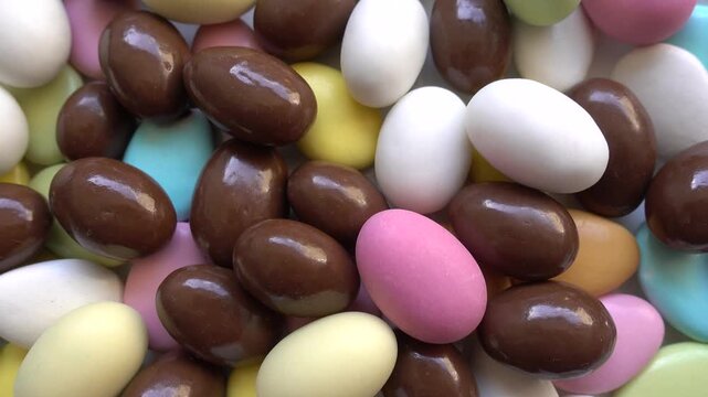 Pile of chocolate-covered almonds or colored pine nut almonds. Easter season.