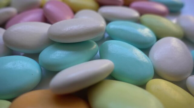 Pile of chocolate-covered almonds or colored pine nut almonds. Easter season.