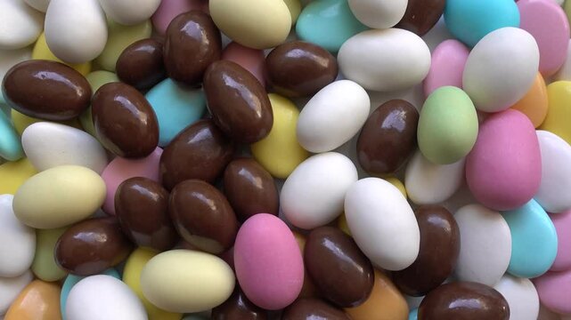 Pile of chocolate-covered almonds or colored pine nut almonds. Easter season.