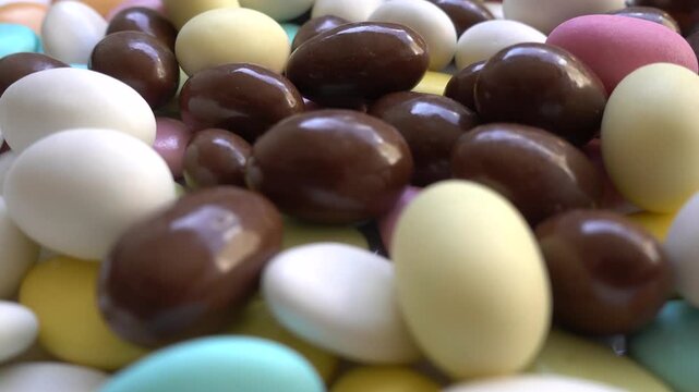Pile of chocolate-covered almonds or colored pine nut almonds. Easter season.