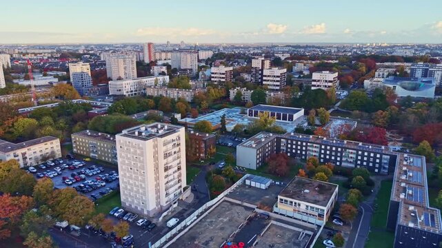 Jean Normand square, the conservatory, and residential buildings in the Le Blosne district during a golden sunrise in Rennes, France. Aerial drone panoramic view
