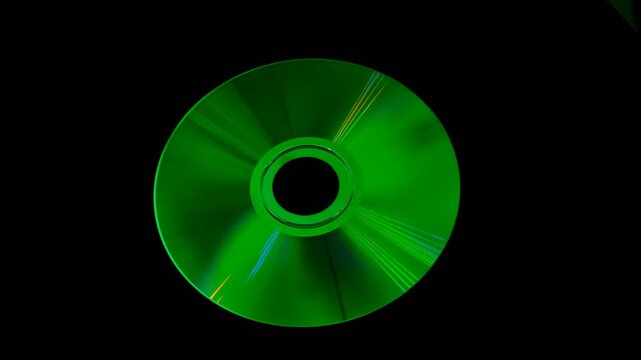 A shiny compact disc reflecting rainbow colors on dark background