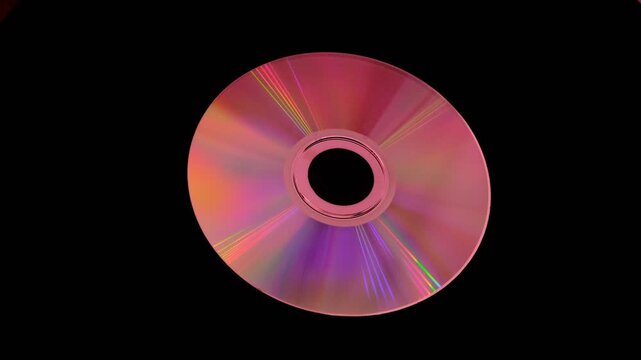 A shiny compact disc reflecting rainbow colors on dark background