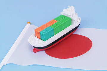Cargo ship with many containers with Japanese flag on blue background.