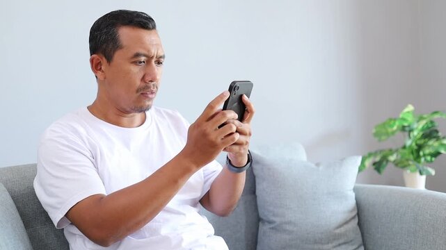 Asian Man, phone and surprised with bad news in home with doubt, shocked with smartphone for online announcement