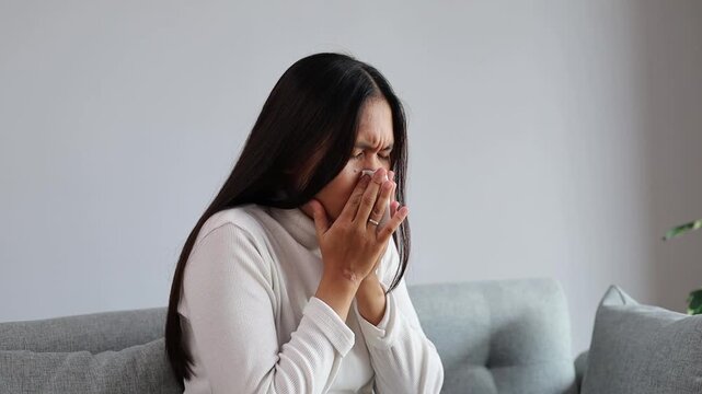 Asian Woman sick with blowing nose sneezing with tissue for infection