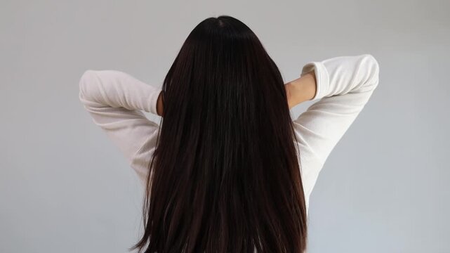 Rear view of young Asian girl shakes, fluttering long straight hair