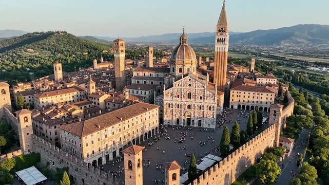 Aerial view of an ancient walled city with a grand cathedral and tall bell
