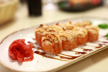 Baked sushi rolls with ginger served on ceramic plate