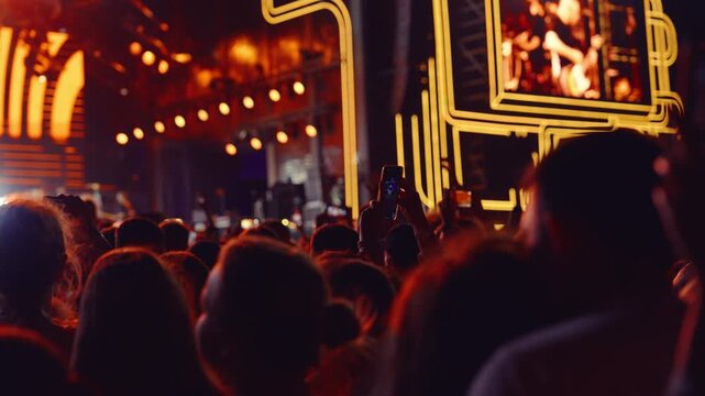 Crowds gather for live concert under lights in bustling outdoor venue at night