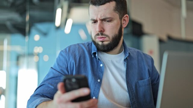 Professional experiences surprise and shock viewing content on smartphone. Confused expression changes to disbelief, bewilderment in modern office. Unsettling news creates strong emotional response.