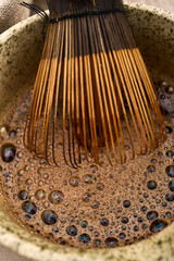Bamboo whisk preparing foamy matcha green tea
