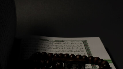 Sacred Scripture and Beads: A close-up view presents a prayer beads draped over an open religious...