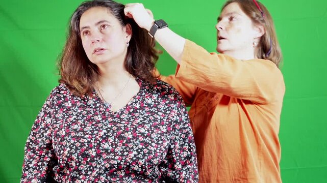 Green Screen. Two women are combing their hair, side view with chroma key background