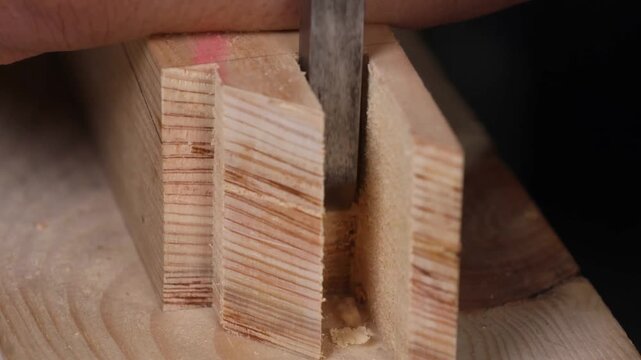 A skilled woodworker uses a chisel to refine square mortise joints