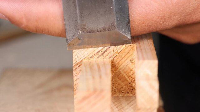 A skilled woodworker uses a chisel to refine square mortise joints