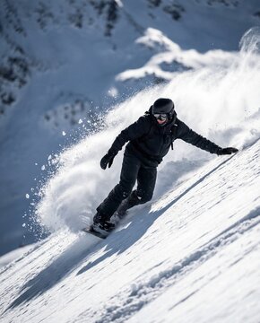 Snowboarder rides down snowy mountain slope on clear day