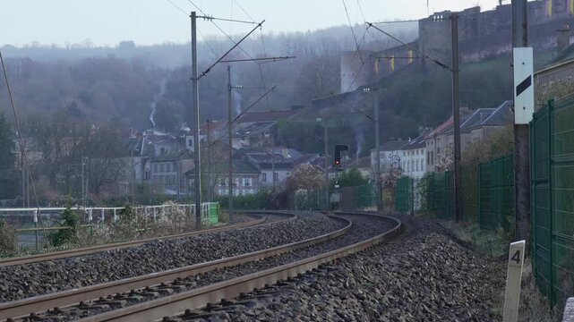 railway station rail tracks in France countryside travel, houses with smoke coming out of the chimneys in the background