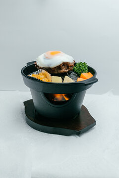Japanese hamburger steak with fried egg on hot iron skillet with flame