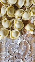 Top view of raw homemade dumplings pelmeni on a wooden board with flour.