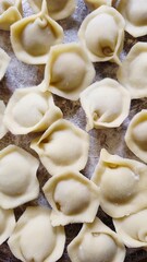 Top view of raw homemade dumplings pelmeni on a wooden board with flour.