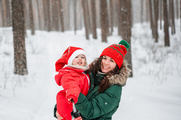 Fototapeta premium Little child girl in hat and winter jumpsuit with her mother outdoor in snow, family
