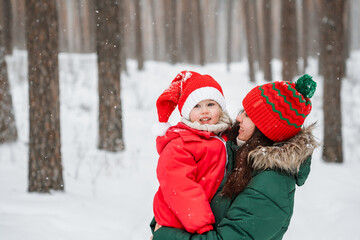 Fototapeta premium Little child girl in hat and winter jumpsuit with her mother outdoor in snow, family