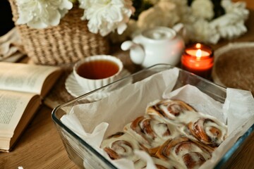 Cozy morning scene with freshly baked cinnamon rolls, tea, and an open book