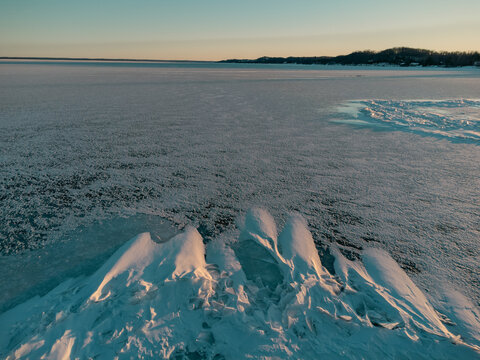 Drone view of ice-covered lake and winter landscape in Michigan
