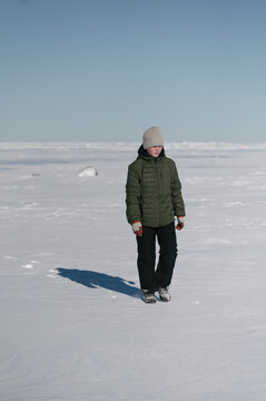 Child explores frozen landscape on sunny winter day