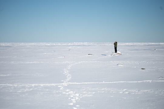 Person standing alone on rock on bright snowy winter day