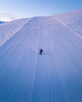 Snowboarder rides on a groomed slope at a ski resort in winter