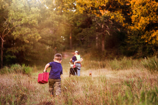 Boy Running to Catch up with family holding a tackle box
