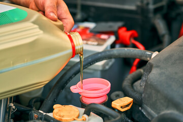 Worker pouring petroleum oil into auto engine