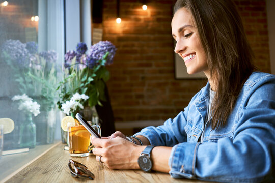 Smiling young woman using phone in cafe