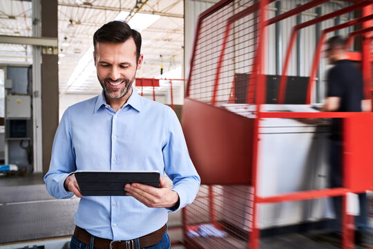 Smiling businessman using tablet in a factory
