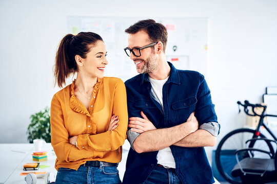 Two smiling colleagues in office facing each other