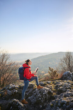 Woman on a hiking trip in the mountains holding map and enjoying beautiful view