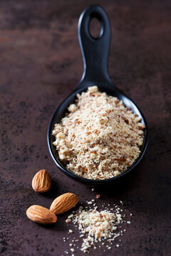 Spoon of almond flour and almonds on rusty ground