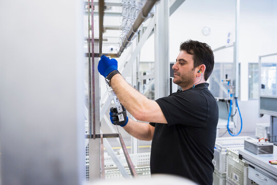 Man working in factory shop floor hanging products on rack