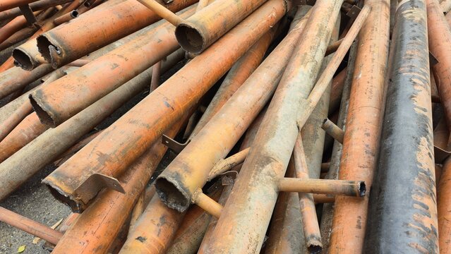 Rusty scrap metal pipes for recycling in a junkyard. A heap of rusty scrap iron and old metal pipes ready for recycling or salvage in an industrial junkyard setting.